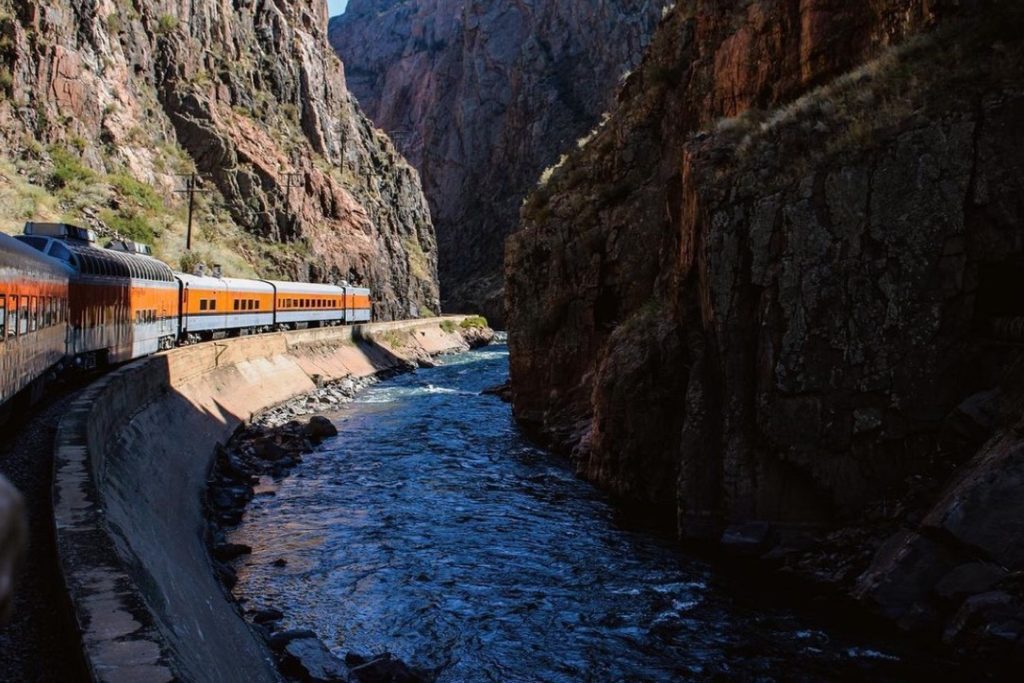 Scenic train driving past a river in Royal Gorge canyon